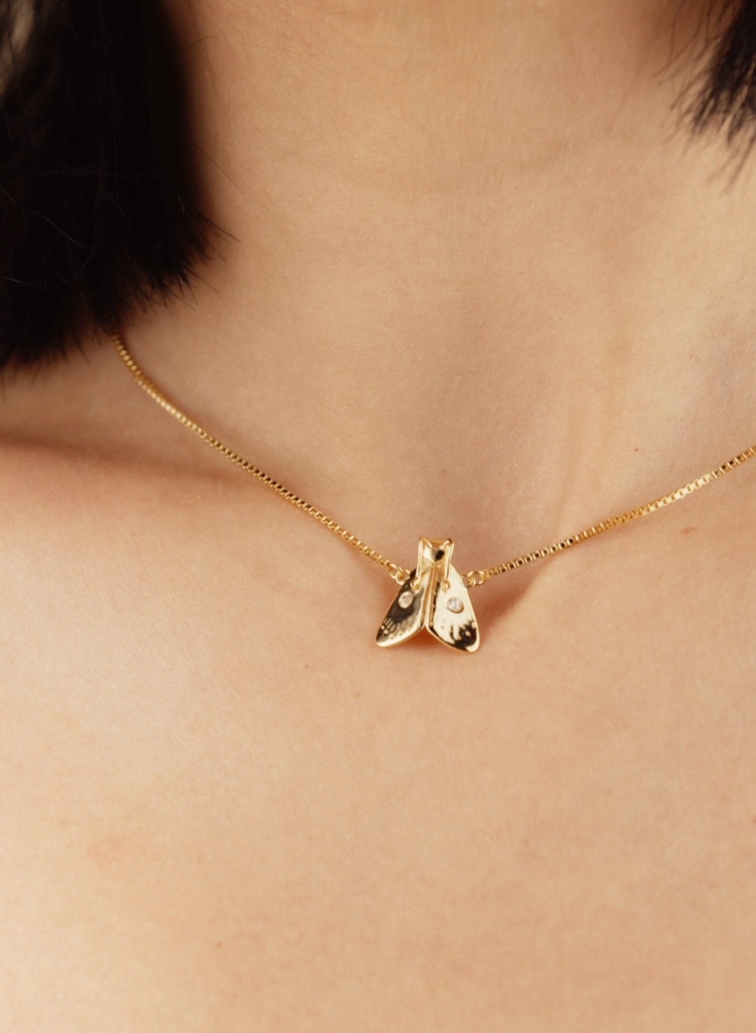 Gold necklace with a pendant worn close to the neck, showcased on a model&#39;s bare skin