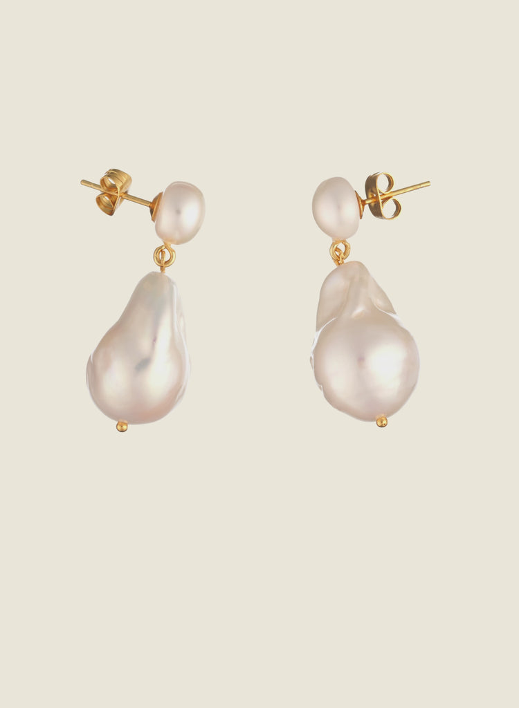 Baroque pearl earrings with gold studs on a cream background